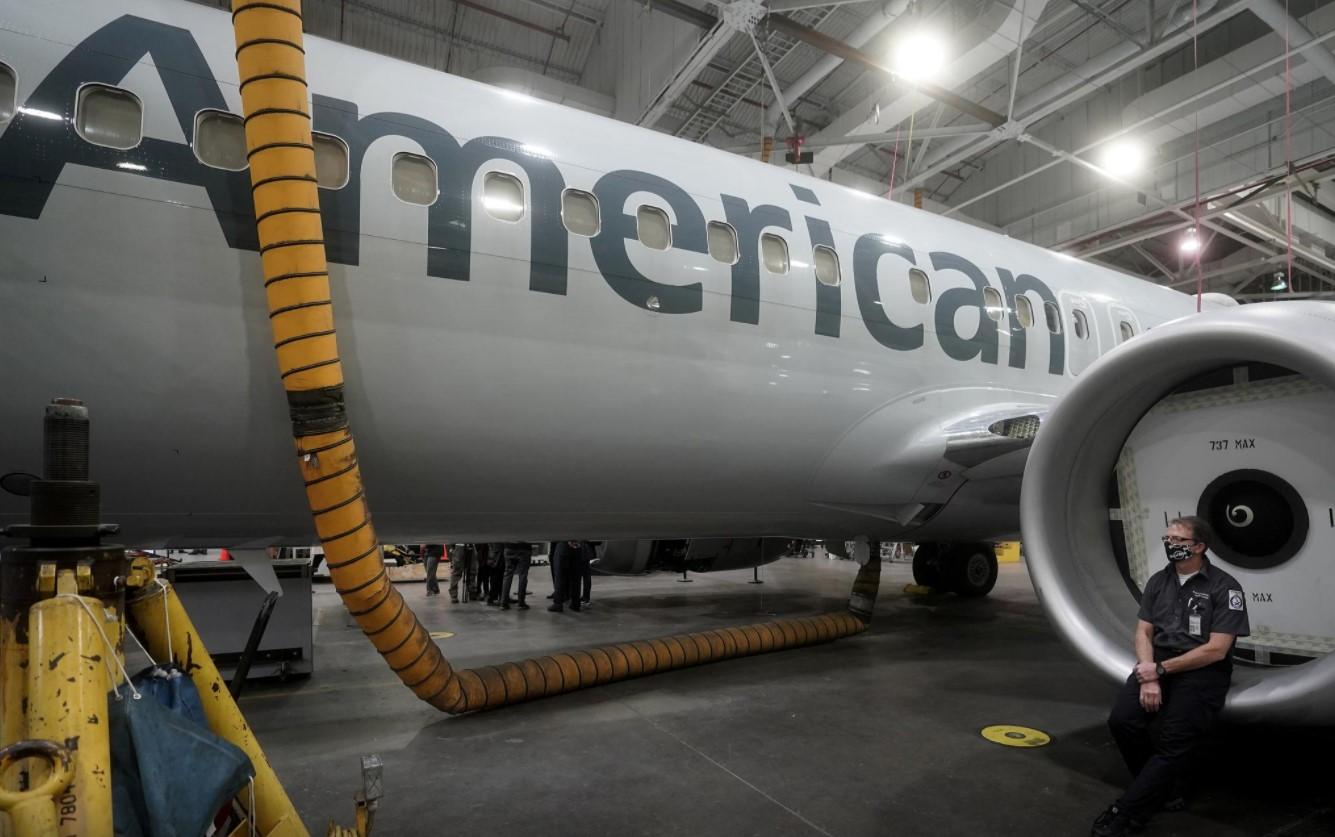 An American Airlines worker sits on an engine cowl of a Boeing 737 Max airplane in a maintenance hanger in Tulsa, Oklahoma, U.S., December 2, 2020. - Avaz